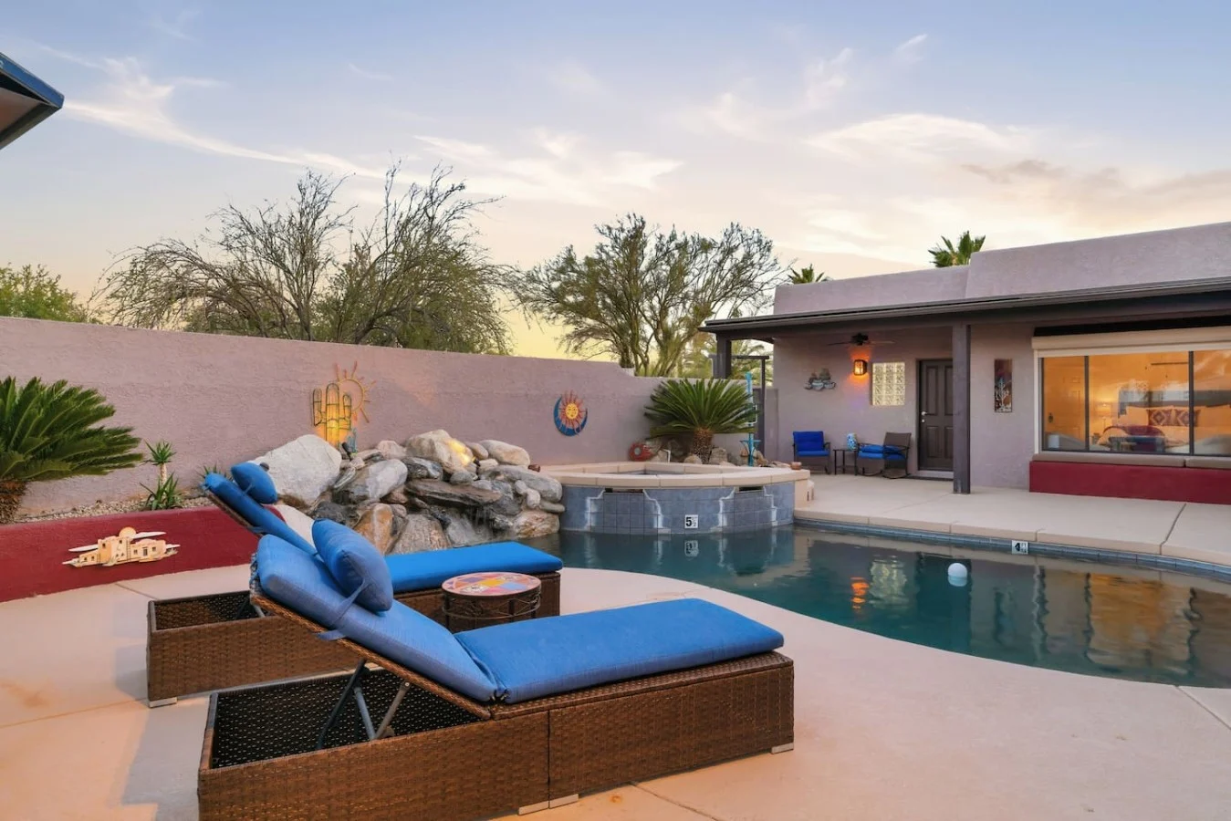 Tucson vacation home with a pool, covered patio and desert landscaping at sunset